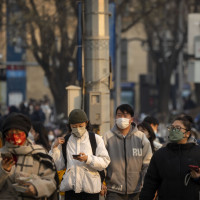 Commuters wearing face masks walk along a street during the morning rush hour in the central business district in Beijing, Thursday, Feb. 16, 2023.