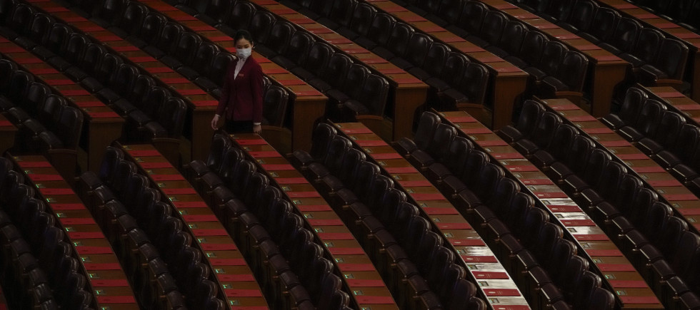 A hostess gives a final check on the reports placed on tables ahead of the closing session of the National People's Congress (NPC) at the Great Hall of the People in Beijing, Monday, March 11, 2024. 